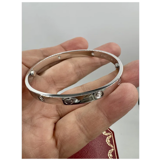 Silver bracelet held in a hand against a neutral background