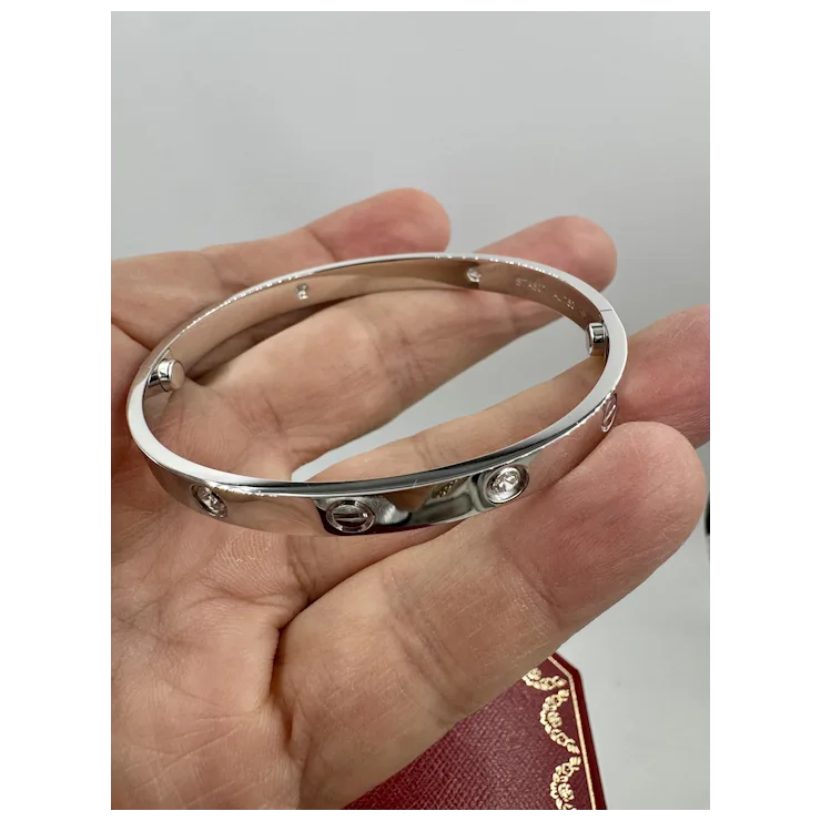 Silver bracelet held in a hand against a neutral background