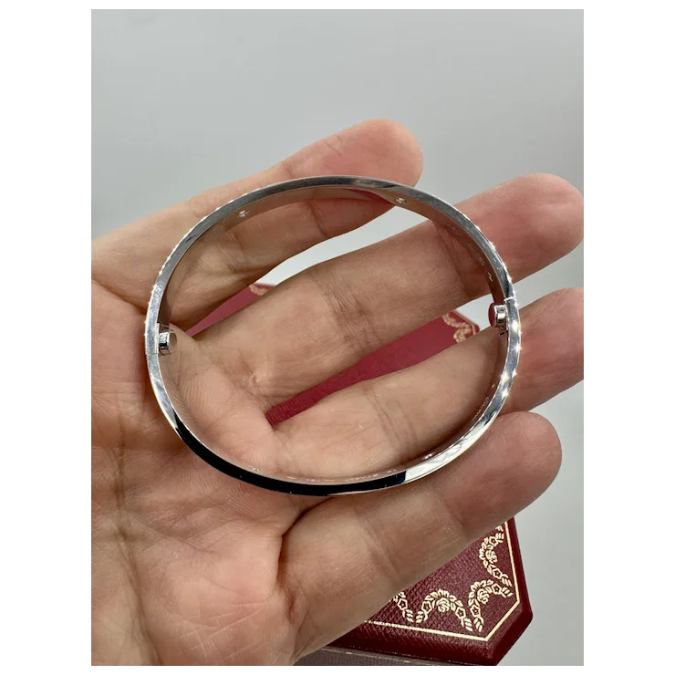Silver ring held in a hand with a plain background