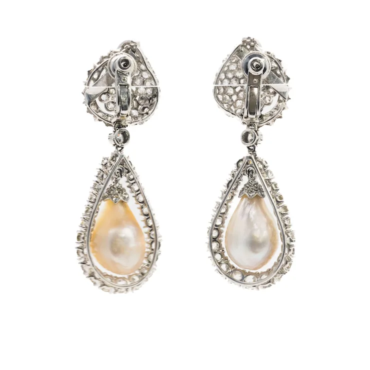 Pair of teardrop-shaped pearl earrings with silver and gemstone detailing on a white background