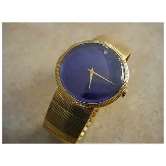 Gold wristwatch with a blue face on a beige background