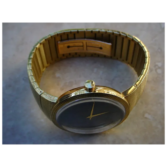 Gold wristwatch with a dark face on a textured surface