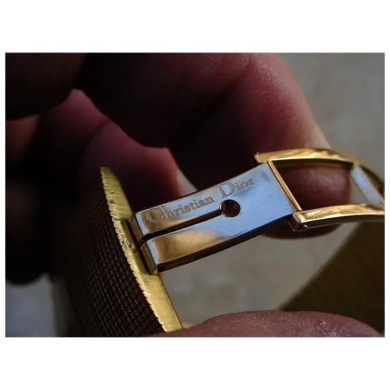 Close-up of a gold and silver Christian Dior belt buckle.