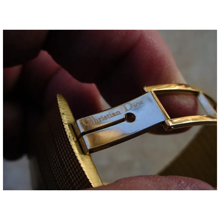 Close-up of a gold and silver Christian Dior belt buckle.
