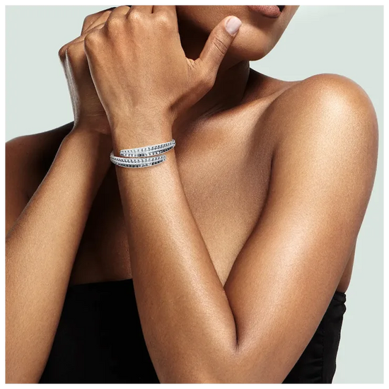 Close-up of a person's arm wearing multiple bracelets on a neutral background