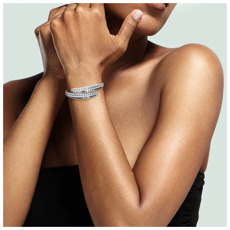Close-up of a person's arm wearing multiple bracelets on a neutral background