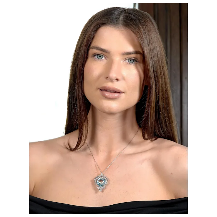 Woman wearing a necklace with a heart-shaped pendant on a plain background