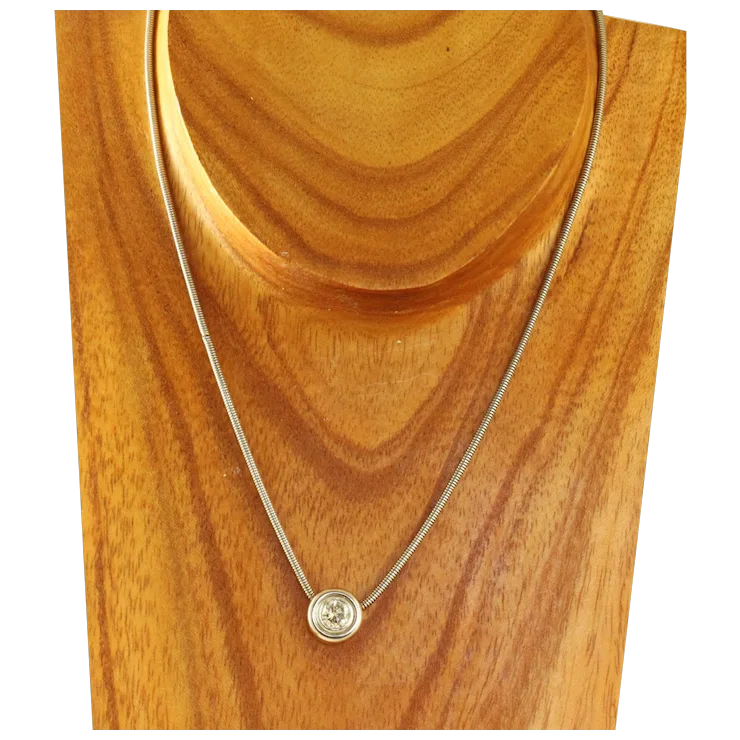 Gold necklace with a round pendant on a wooden stand