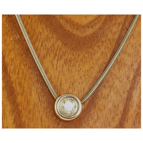 Gold necklace with a round pendant on a wooden surface