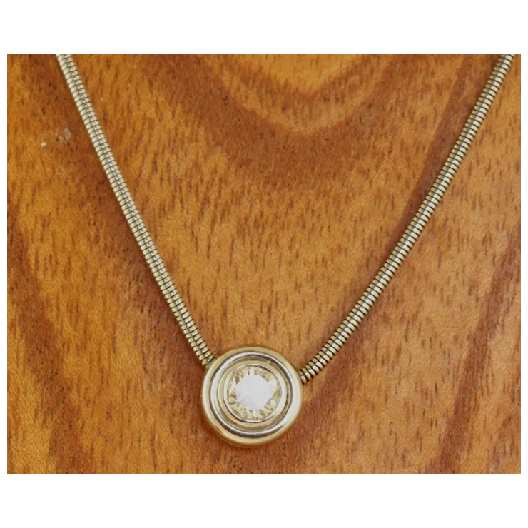 Gold necklace with a round pendant on a wooden surface