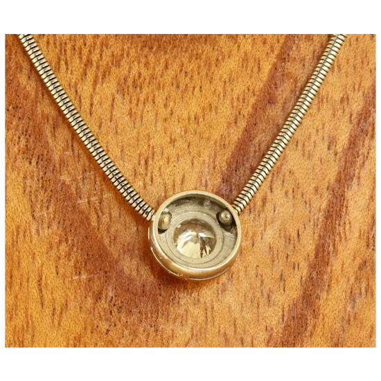Gold necklace with a round pendant on a wooden surface