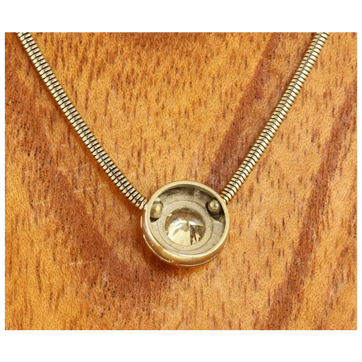 Gold necklace with a round pendant on a wooden surface
