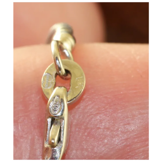 Gold chain bracelet on a person's wrist with visible brand logo.
