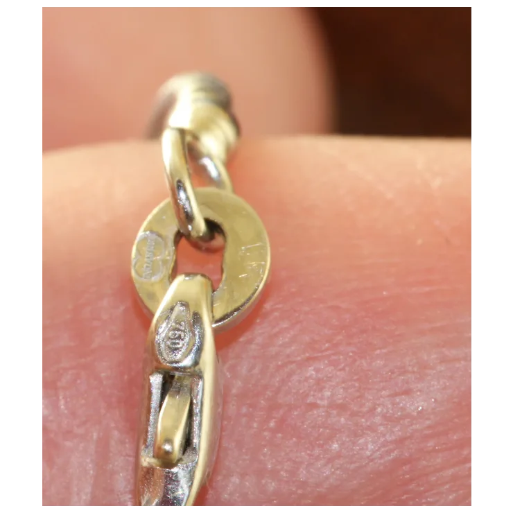 Gold chain bracelet on a person's wrist with visible brand logo.
