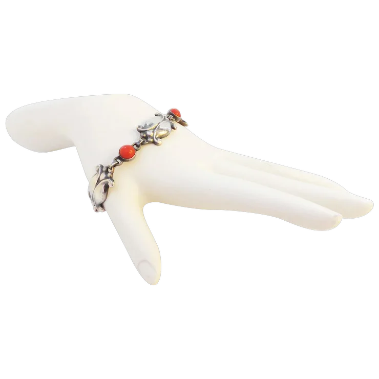 Bracelet with red beads and silver charms on a white mannequin hand