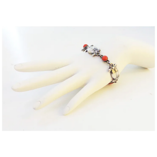 Bracelet with red and white stones on a mannequin hand against a white background