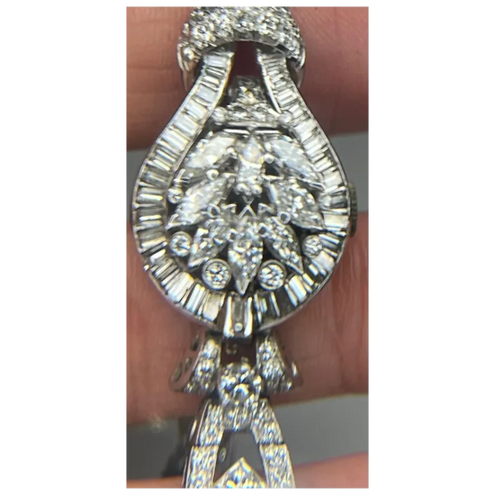 Silver necklace with a large diamond pendant held by a hand.