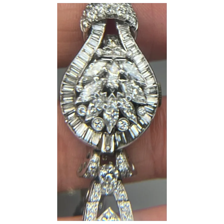 Silver necklace with a large diamond pendant held by a hand.