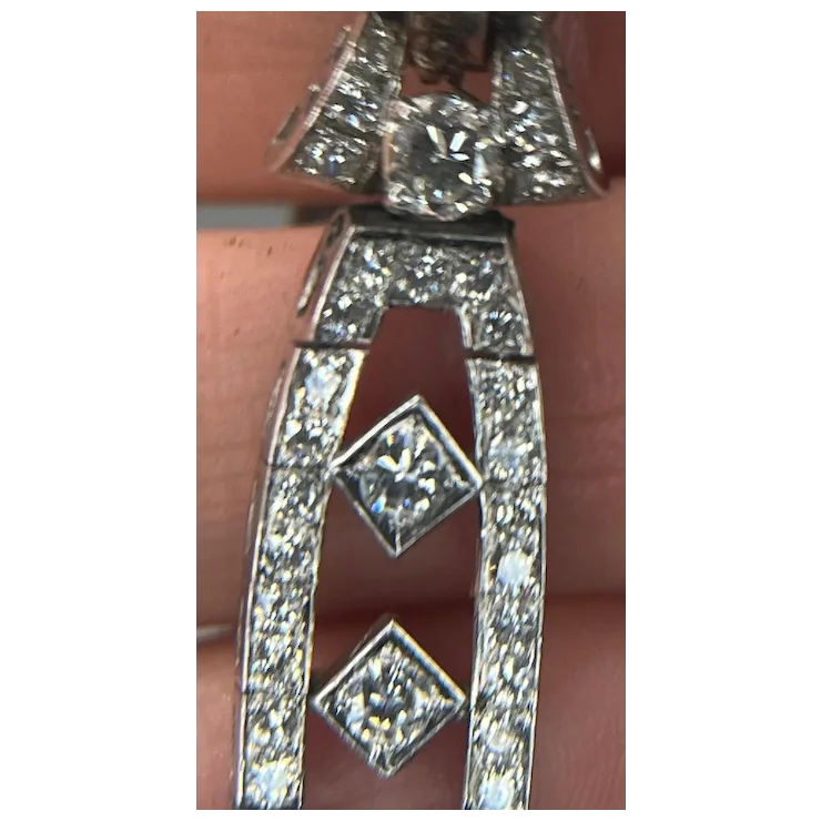 Diamond-encrusted silver pendant held between fingers
