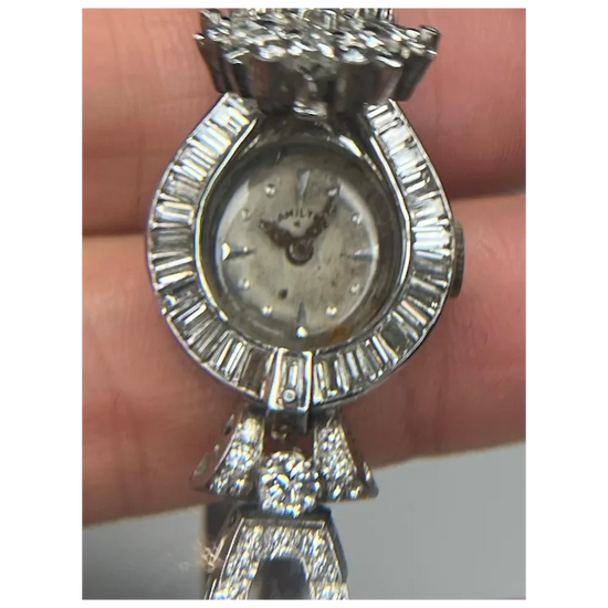 Silver watch with diamond accents held by a hand