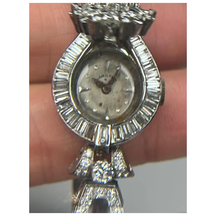 Silver watch with diamond accents held by a hand