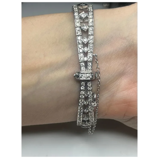 Silver bracelet with clear stones on a wrist against a neutral background