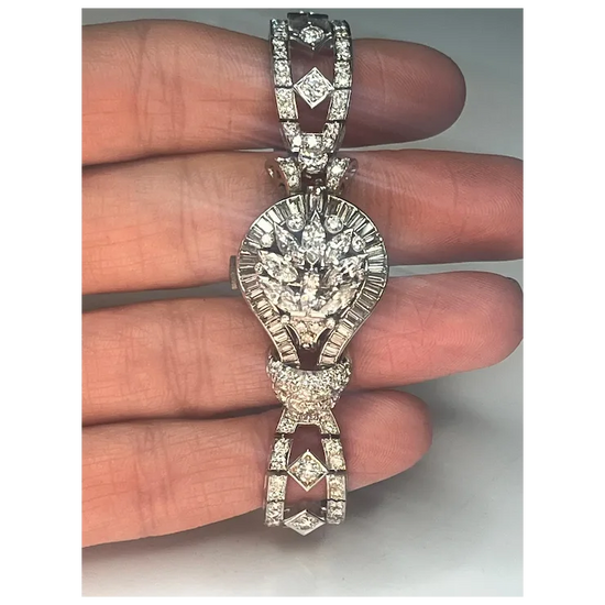 Diamond-encrusted necklace held between fingers against a neutral background