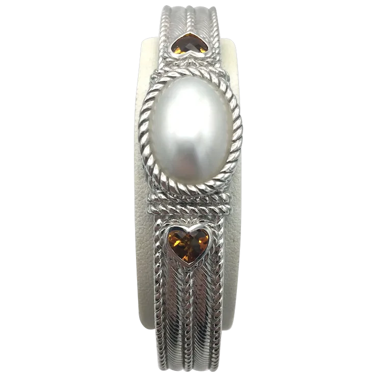 Silver ring with a pearl and heart-shaped gemstones on a white background