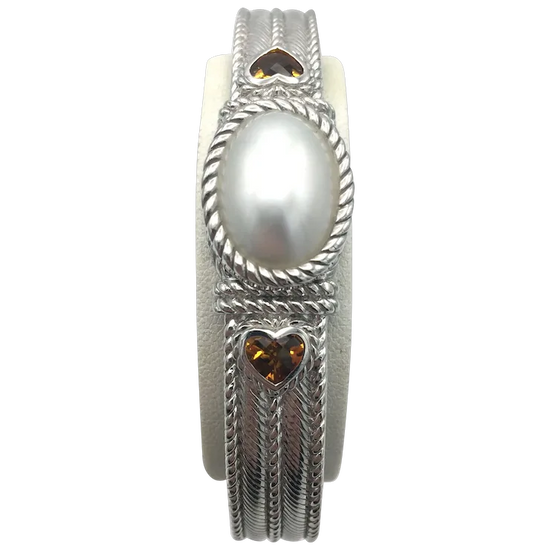 Silver ring with a pearl and heart-shaped gemstones on a white background