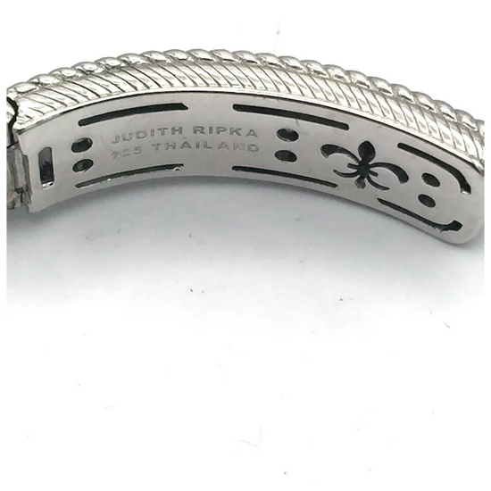 Close-up of a silver bracelet with 'Judith Ripka' engraving on a white background