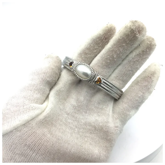 Silver ring with a pearl on a gloved hand against a white background