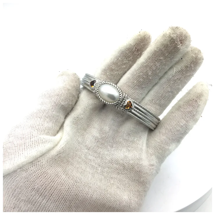 Silver ring with a pearl on a gloved hand against a white background