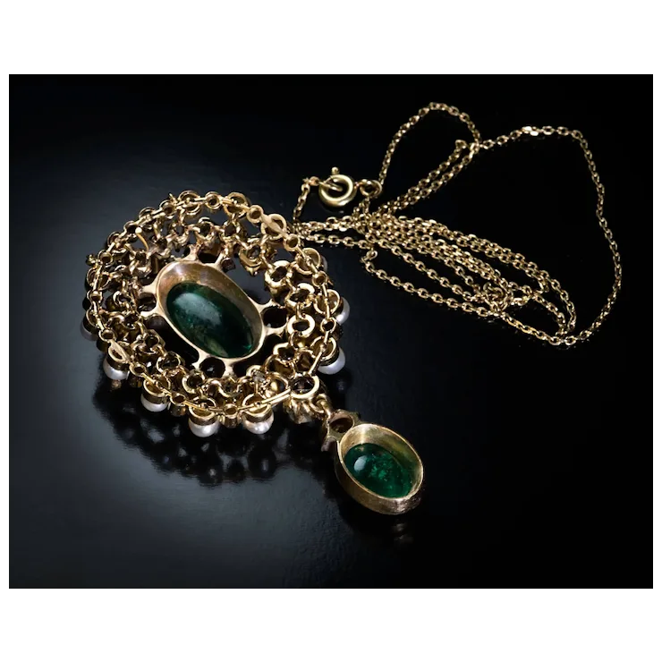 Gold necklace with green gemstones on a black background