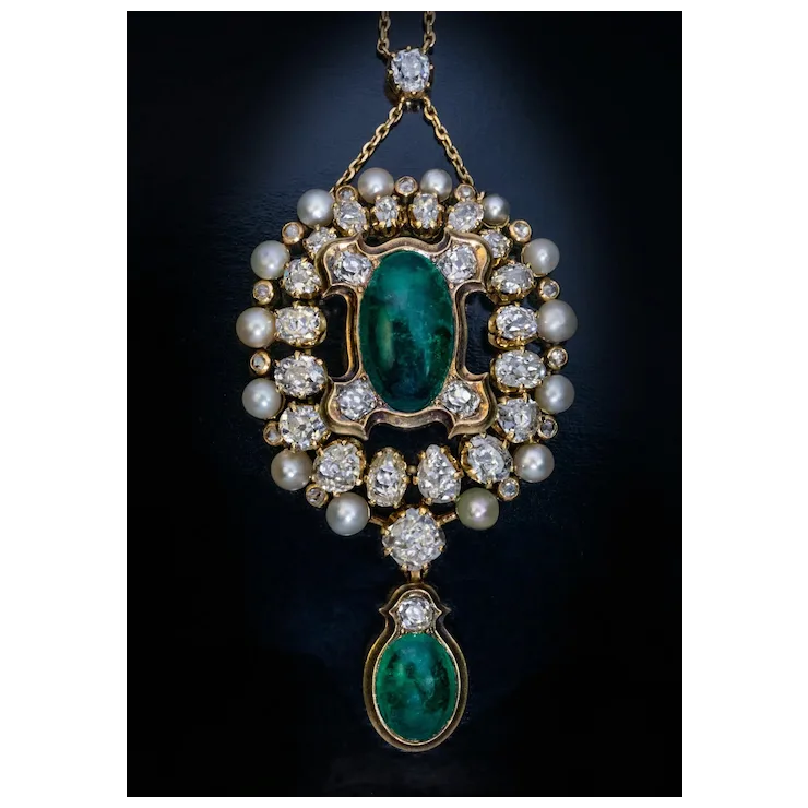 Vintage-style pendant with emerald stones, pearls, and diamonds on a dark background