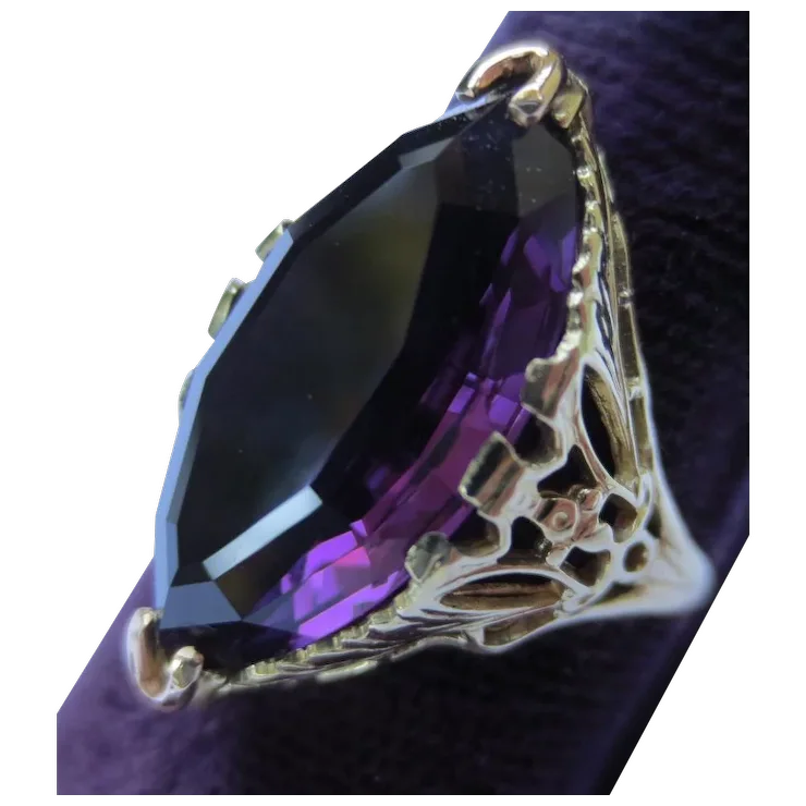 Gold ring with a large purple gemstone on a white background