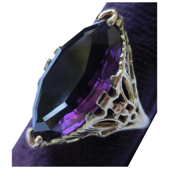 Gold ring with a large purple gemstone on a white background