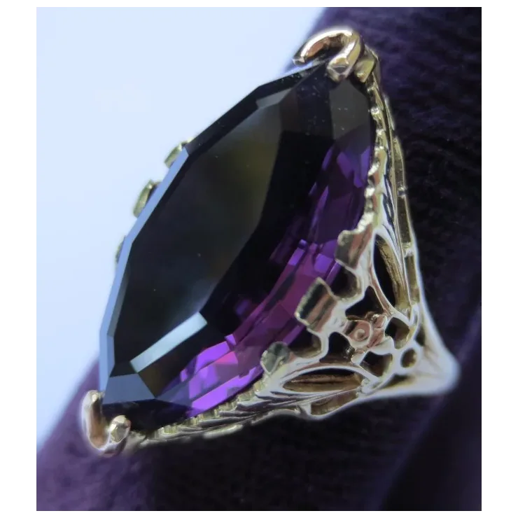 Purple gemstone pendant with gold setting on a dark background