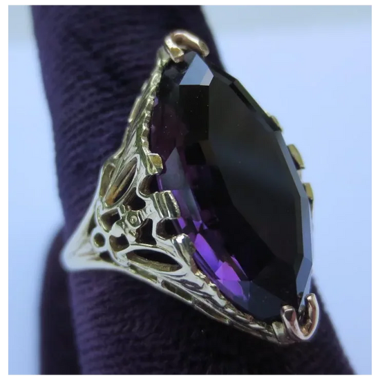 Ring with purple gemstone and gold band on a textured surface