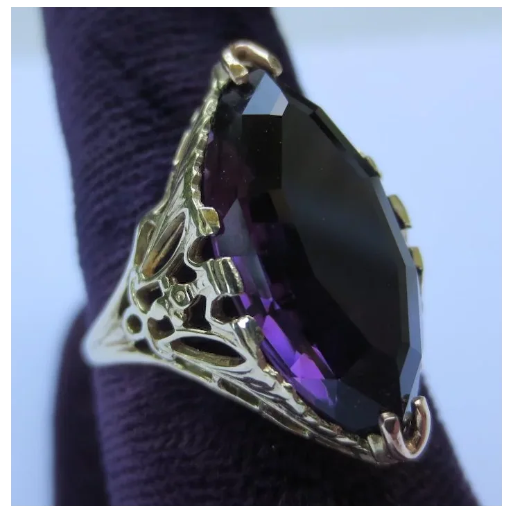 Ring with purple gemstone and gold band on a textured surface