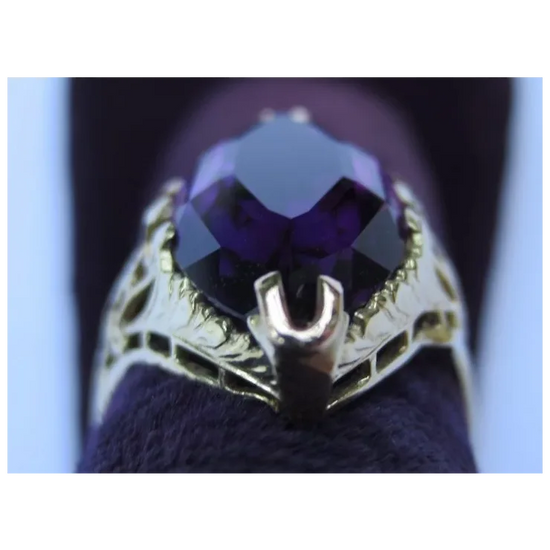 Gold ring with a purple gemstone on a dark background