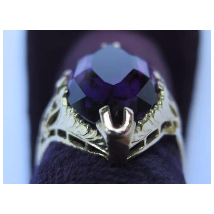 Gold ring with a purple gemstone on a dark background