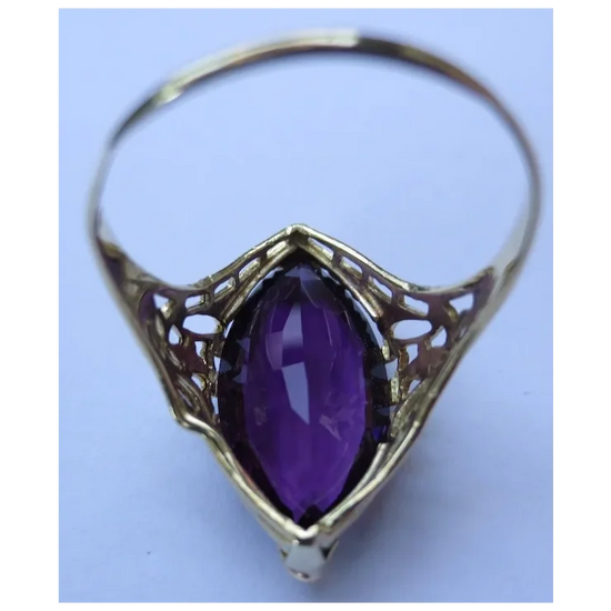 Gold ring with a purple gemstone on a light blue background