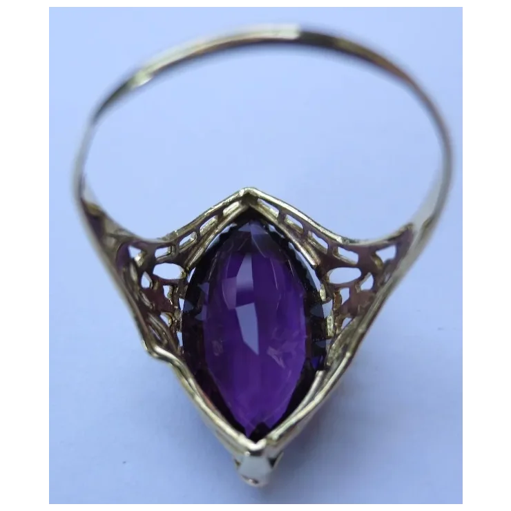 Gold ring with a purple gemstone on a light blue background