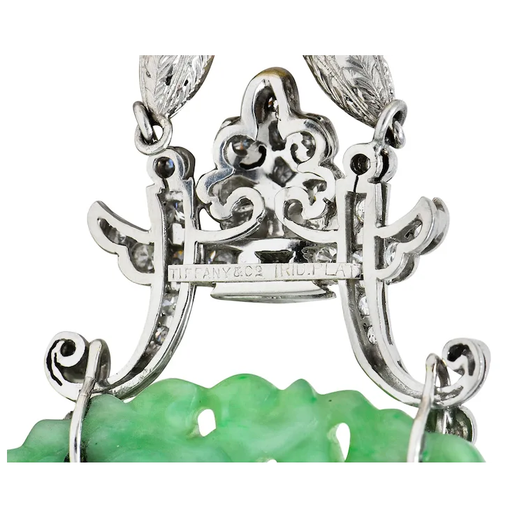 Close-up of a silver necklace with green pendant on a white background