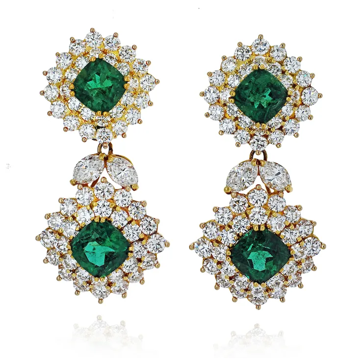 Pair of earrings with green gemstones and gold accents on a white background