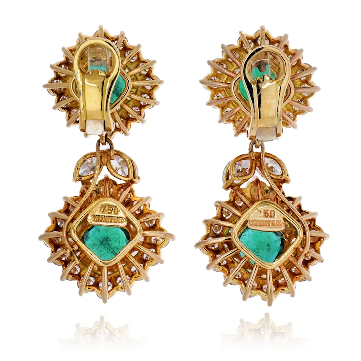 Gold earrings with green gemstones on a white background