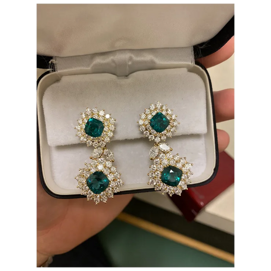Pair of emerald green gemstone earrings in a jewelry box.