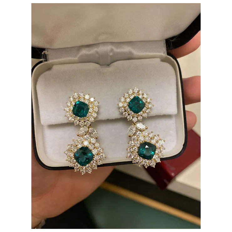 Pair of emerald green gemstone earrings in a jewelry box.