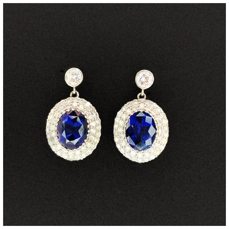 Pair of earrings with blue gemstones and gold accents on a black background