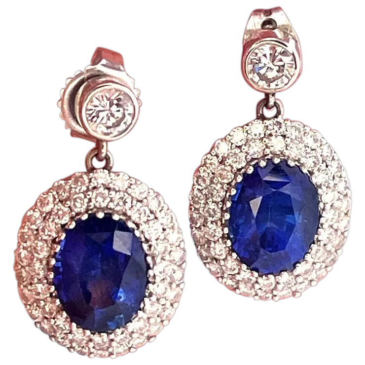 Pair of earrings with blue gemstones and rose gold accents on a white background